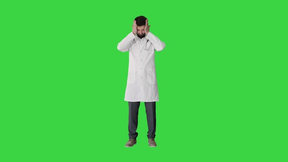 Вepressed Doctor Holding His Head on a Green Screen, Chroma Key.