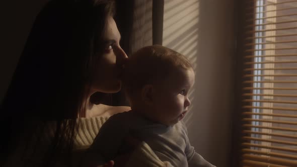The Child in the Arms of the Mother Looks Out the Window