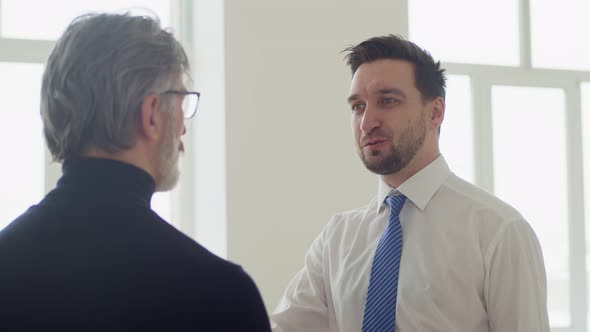 Real estate agent man talking to businessman client about renting an office space, front view.