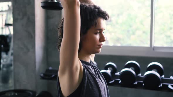 Fit Woman Doing Overhead Triceps Extension Exercise with Dumbbell at the Gym