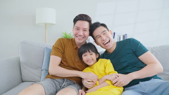 Portrait of handsome man gay family with young daughter and look at each other in living room house.