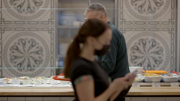 Senior Man in Covid19 Face Mask Walking with Food Tray To Camera As Blurred Waitress Passing at