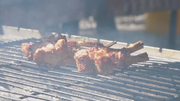 Professional Cook Puts Pork Rib on Barbecue Grid with Tongs