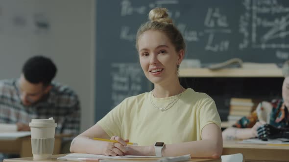 Portrait of Happy Female Student at Desk in College