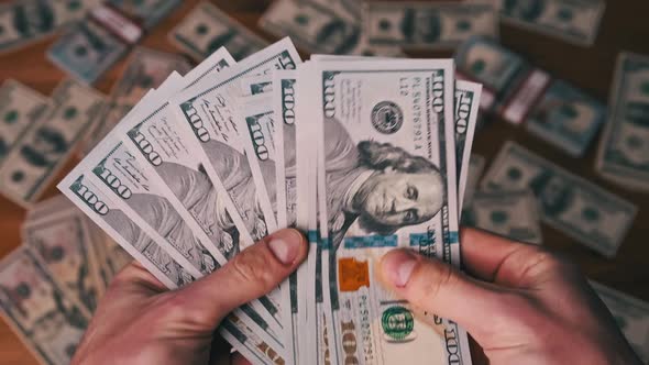 Dollars in Male Hands on Background of Table with Money Counting Banknotes