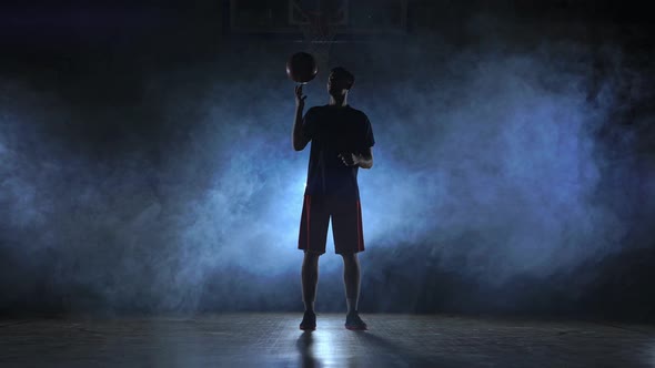 Close Footage of Basketball Player Spinning Ball on His Finger, Dark Misty Room with Floodlight