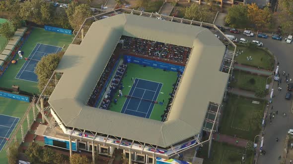 slow orbiting aerial view of a live tennis match playing out in a stadium