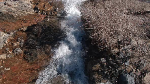 Aerial view looking down at water as it falls over small cliff