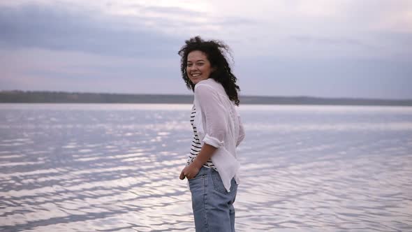 Smiling Young Brunette Caucasian Woman in White Shirt and Jeans Holding Hands in Pockets Feeling