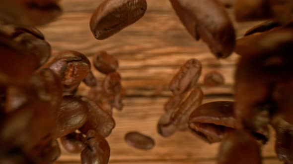 Super Slow Motion Detail Shot of Coffee Beans Falling Down on Wooden Background at 1000Fps