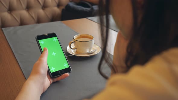 Woman Using Mobile Cell Phone with Green Touch Screen in Cafe