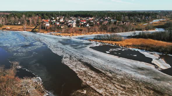 Small Town at Bank of River Gauja with Melting Ice and Snow in Spring Rising Shot