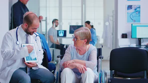 Doctor Explaining Diagnosis To Elderly Woman in Wheelchair