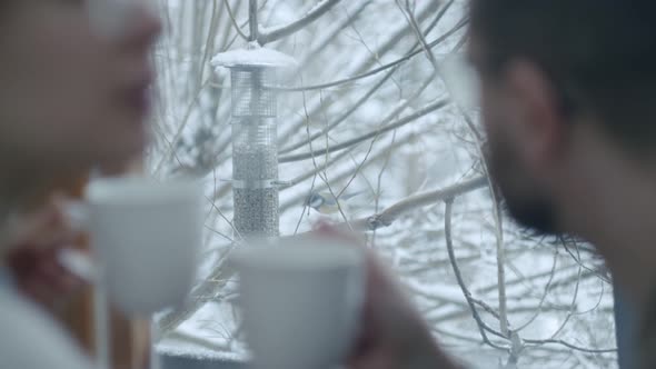 a Couple Watching Birds Outside the Window Drinking Tea or Coffee