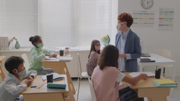 Teacher Handing Out Test Sheets to Children in Class