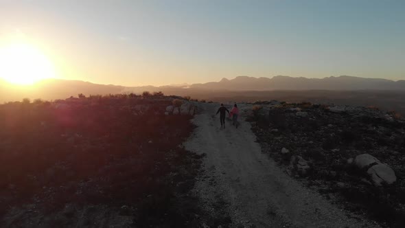 Young couple on a road trip running to top of mountain at dusk