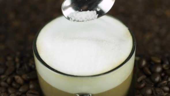 Pour Spoon of Sugar in Coffee Foam, Natural Beans Background. Latte Ingredients