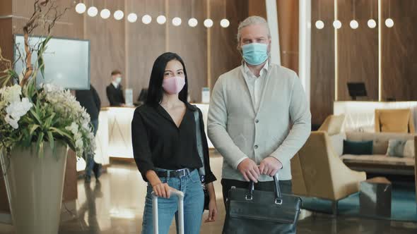 Couple in Face Masks in Hotel Lobby