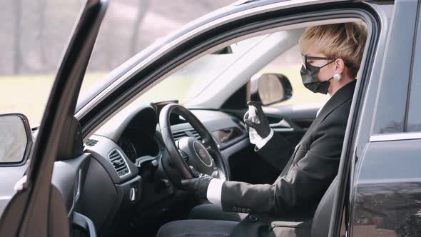 The Woman in a Disposable Mask Is Disinfecting Her Car with Antiseptic