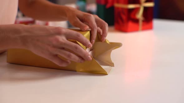 Closeup Side View Hands of Unrecognizable Young Woman Wrapping Festive Christmas Gift Box in Craft