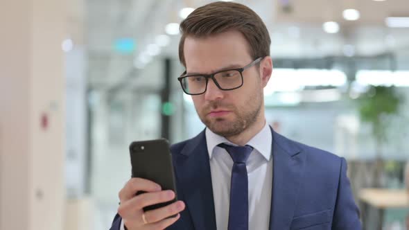 Businessman Browsing Internet on Smartphone at Work