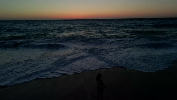 Woman Enjoying Sunset Above the Sea with Big Waves