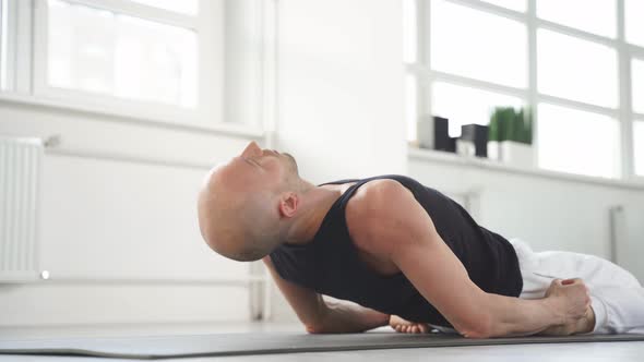 Experienced Bald Caucasian Yoga Man Doing Various Yoga Poses Indoors