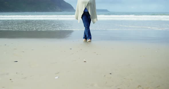 Senior woman standing with hands raised on beach