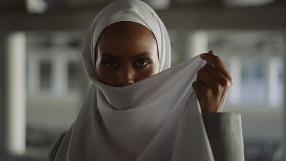 Languid Black Lady Hides Face with Headscarf on Embankment