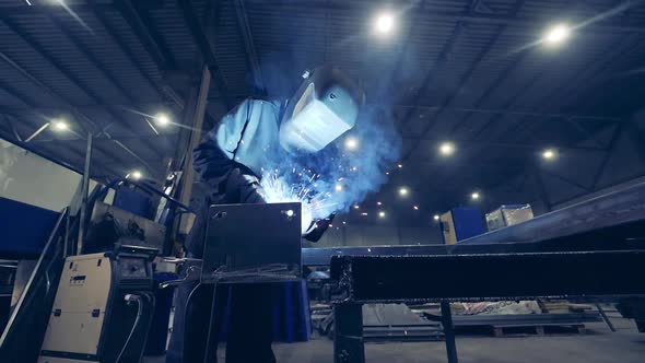 Factory Worker Welds with a Machine.
