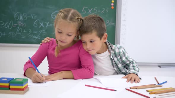 School Love, Classmates Write During Lesson at Table and Then Look at Camera and Smile on Background