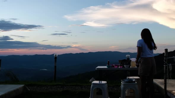 A woman preparing dinner with evening sky and mountain views