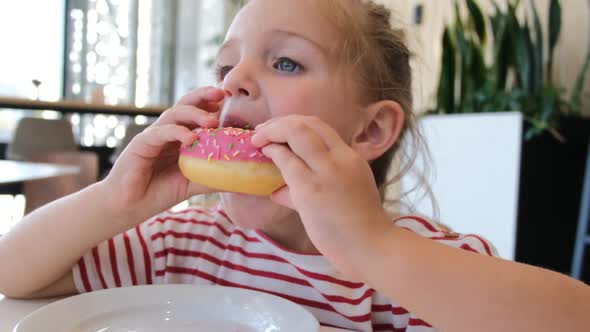 Cute Little Girl Eating Pink Donut