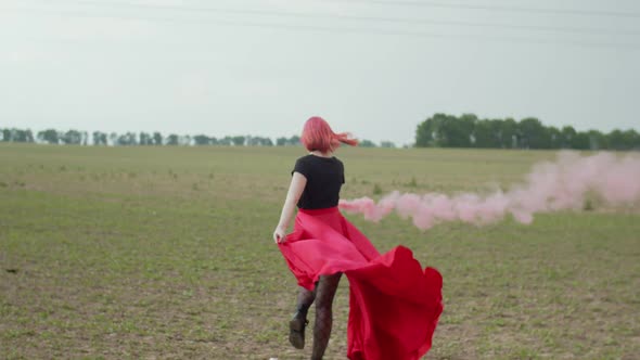 Stylish Woman Walking Across Field with Smoke Bomb