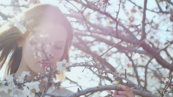 Beautiful Young Woman in the Sun Inside the Flowering Tree