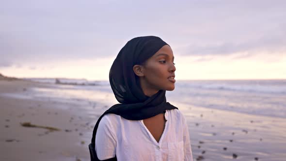 Somali-American woman walking on the beach at sunset