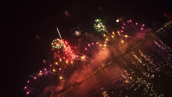 Colorful Fireworks Burst in Air Reflecting on Water Surface