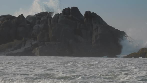 Heavy Ocean Wave Beats on Grey Rocks Near Tropical Coast