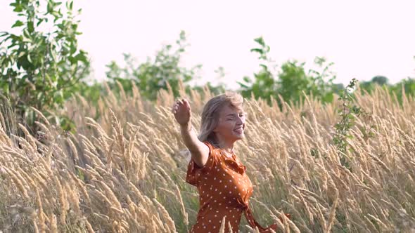 Attractive Fun Hippie Blonde Woman in the Field at Sunset Having Good Time Outdoors