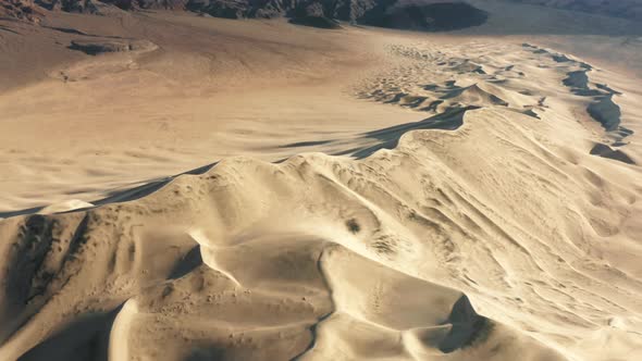 Aerial Fast b Roll Shot of Sand Dunes with Snowy High Mountains at Sunset  USA