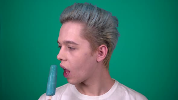 Young Man Eating Ice Cream Enjoying Sweets Isolated on Blue Background