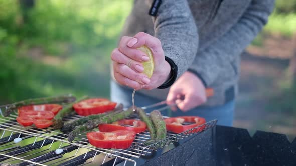 Making Grilled Vegetables  Adding Lomon Juice to Asparagus and Red Pepper on a Charcoal Grill