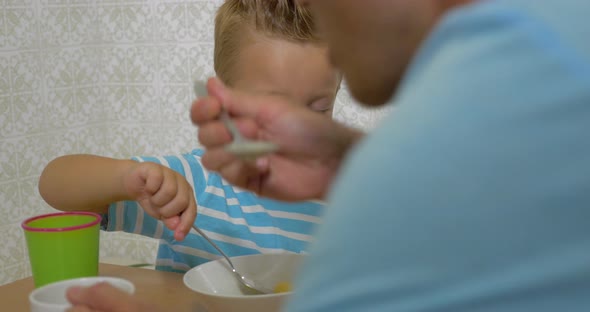 Father teaching son to use a spoon during eating