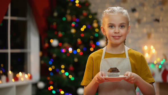 Adorable Girl Showing Muffin at Camera and Smiling, Happy Xmas Atmosphere