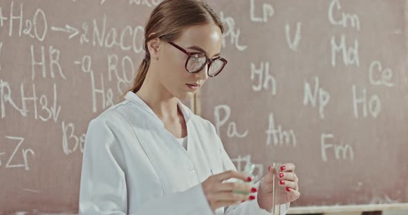 Beautiful Young Woman Conducting Chemical Experiments in a Vintage Laboratory Near a Board