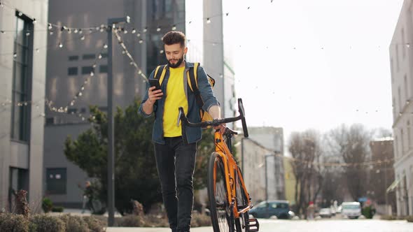 The Food Delivery Guy is Going and Looking at the Smartphone