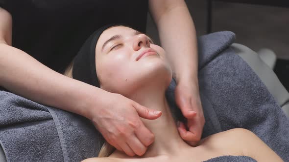 An Attractive Woman Lies on a Bed in a Beauty Salon and Gets a Massage on the Decollete and Neck