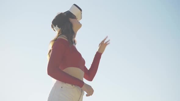 Middle Shot Portrait of Young Absorbed Woman Using Virtual Reality Simulator Outdoors. Slender