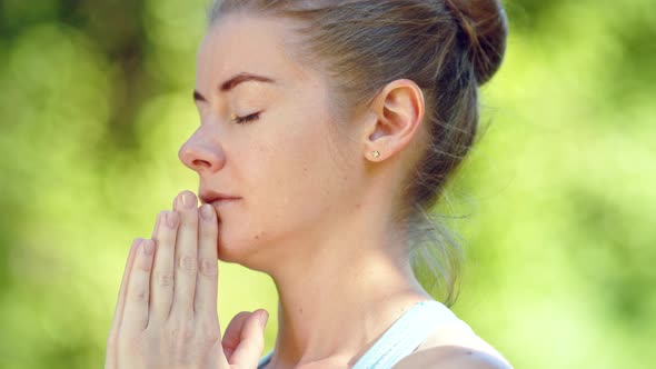 Concentrated young woman blonde meditates in yoga pose joining hands in namaste asana