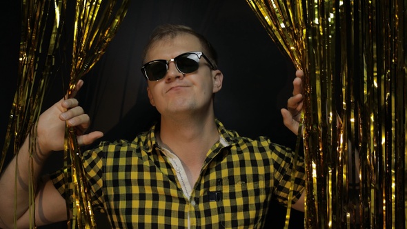 Portrait of Caucasian Man Dancing on Black Background. Gold Shining Foil Strips. Party, Music, Disco